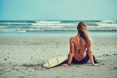Craving the ocean. a beautiful young woman going for a surf at the beach.の写真素材