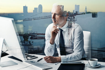 Building his business on a solid foundation. a handsome mature businessman superimposed over a construction site.の写真素材