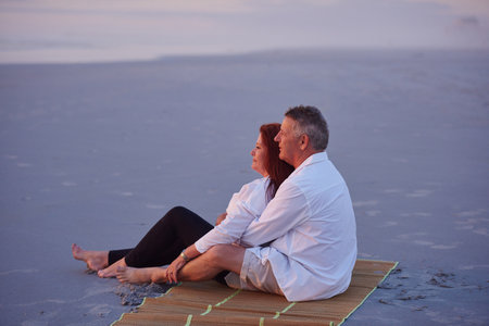 Unplug and unwind. a mature couple relaxing together on the beach.の写真素材