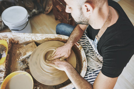Nourish your heart with art. a young man working with clay in a pottery studio.