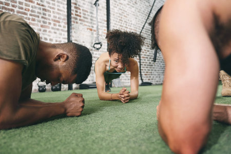 Dedicate yourself to becoming your best. a fitness group planking while working out at the gym.の写真素材