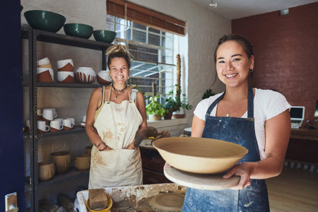 Whats made by you is much more appreciated. two young women making a bowl in a pottery studio.の写真素材