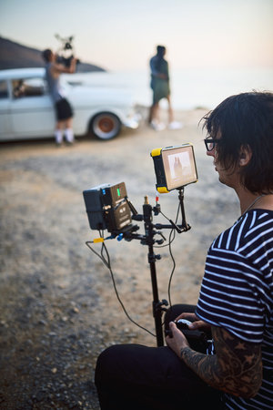 Looking for any mistakes. Over the shoulder shot of a focused young man shooting a scene with a...