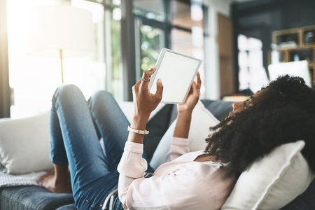 Sofa and wifi, nothing else needed. an attractive young woman relaxing at home.の写真素材