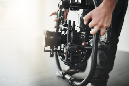 Let the lens do the talking. Behind the scenes over the shoulder shot of an unrecognizable person operating a state of the art video camera inside of a studio.の写真素材
