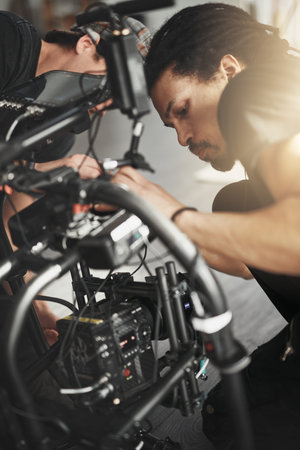 The equipment is almost up and running. Behind the scenes shot of a videographer working on a state...