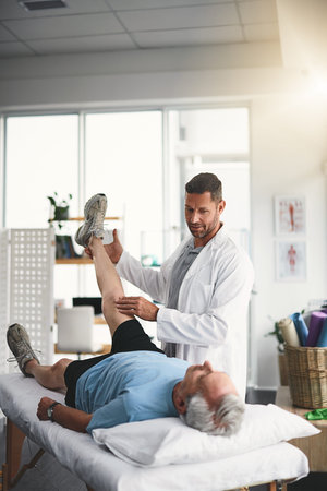Muscles have to be rebuilt with great care. a young male physiotherapist assisting a senior patient...