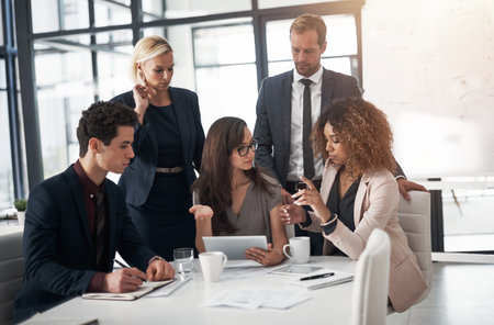 Weve got the resources so lets make use of it. a group of businesspeople using a digital tablet during a meeting in an office.の写真素材