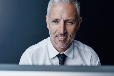 Success makes him smile. a mature businessman working on his computer.