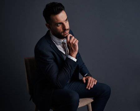 His mind is in profit mode. Studio shot of a stylish young businessman looking thoughtful against a gray background.の写真素材