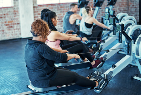 Switching things up in the gym. a fitness group working out on rowing machines in their session at the gym.の写真素材