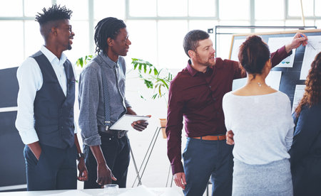 Mapping out the way forward. a group of businesspeople brainstorming in an office.