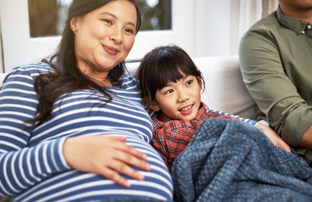 Cosy times. a family watching television together at home.の写真素材