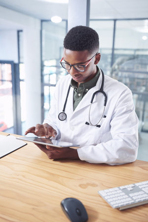 I never miss a detail on reports. a handsome young doctor sitting alone in his office at the clinic...