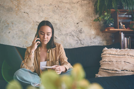 Life changed its course in the middle of quarantine. an unrecognisable woman using a smartphone while taking a pregnancy test on the sofa at home.の写真素材