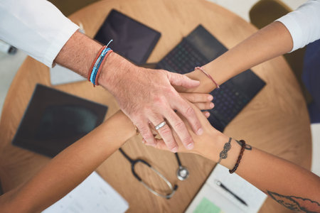 Planning and managing healthcare is a joint effort. Closeup shot of a team of doctors joining their...