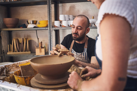 A piece of personality goes into every pot. a young man and woman working with clay in a pottery studio.の写真素材