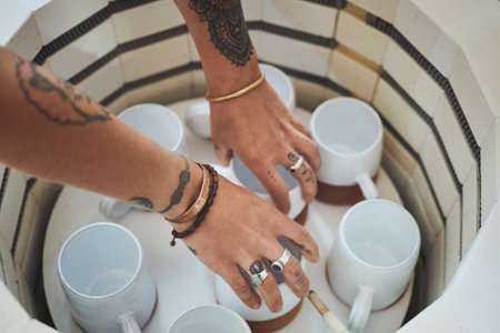 Firing up the electric furnace. an unrecognisable woman using an electric kiln in a pottery studio.の写真素材