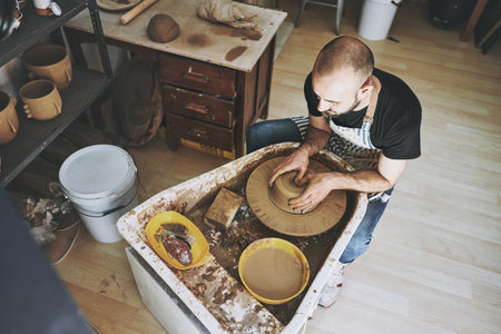 Another day, another masterpiece to make. a young man working with clay in a pottery studio.の写真素材