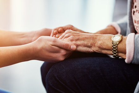 Treating her patients with compassion. an unrecognizable female nurse holding her senior patients hand in comfort.の写真素材