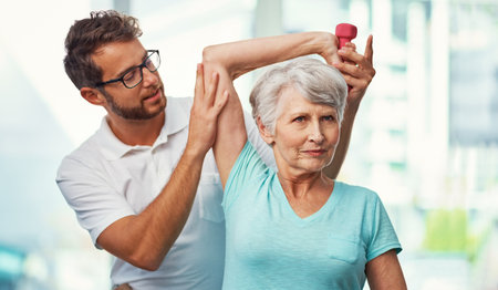 Just a little more...a senior woman working through her recovery with a male physiotherapist.の写真素材