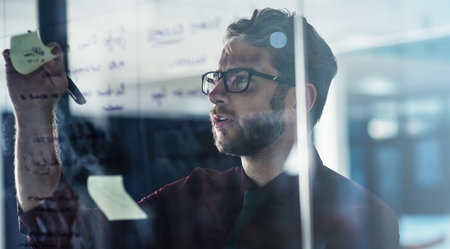 If theres a problem, hell find the solution. a young businessman brainstorming with sticky notes on...