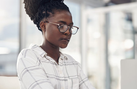 Professional, woman and focus on laptop for entrepreneurship in Africa on the internet. Female employee, reading and computer screen for company with technology and glasses for digital design.の写真素材