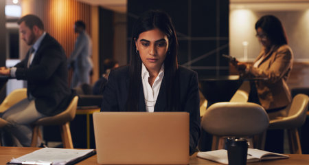 Laptop, corporate lounge and woman reading stock exchange report, finance insight or financial trading analysis. Web review, night and overtime person doing research of online investment marketの写真素材