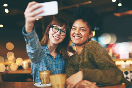 Lets take one with no filter. two young friends taking a selfie together in a cafe.の写真素材