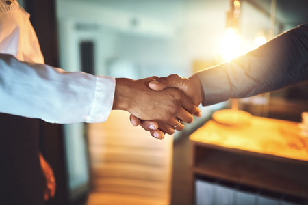 The day was done when they reached a new deal. Closeup shot of two unrecognizable businesspeople shaking hands in an office at night.の写真素材