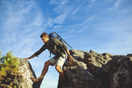 The mountains are his domain. a young man hiking up a mountain.の写真素材