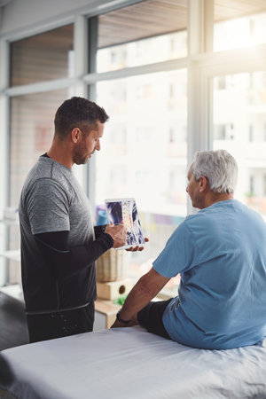 This is whats happening inside your body. a young male physiotherapist assisting a senior patient in recovery.の写真素材