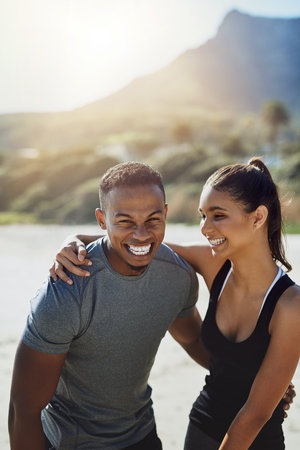 Being healthy truly does make you feel happier. a sporty young couple exercising at the beach.の写真素材
