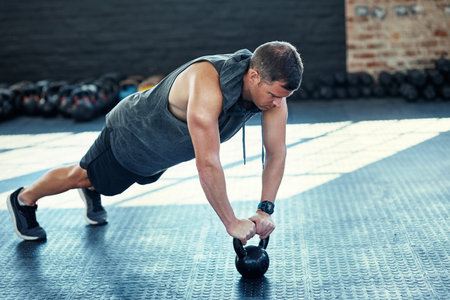 I am in control of the body I want. a young man doing push ups with kettlebells in a gym.