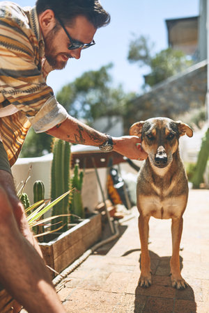 Who wants to go for a walk. a cheerful young man petting his dog outside of his home during the day.の写真素材