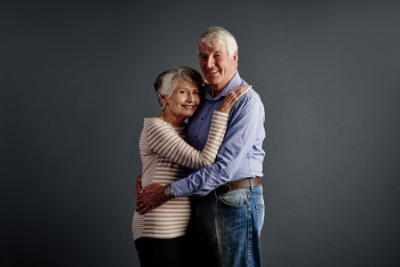 The two of us, to the end of time. Studio portrait of an affectionate senior couple posing against a grey background.の写真素材