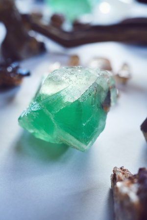 Such a beautiful color. Closeup of a beautiful green crystal placed on a table with other different...