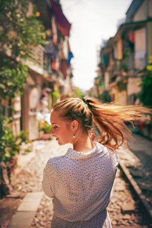 Leave the monotony of life behind you. a young woman walking on train tracks through the streets of Vietnam.の写真素材