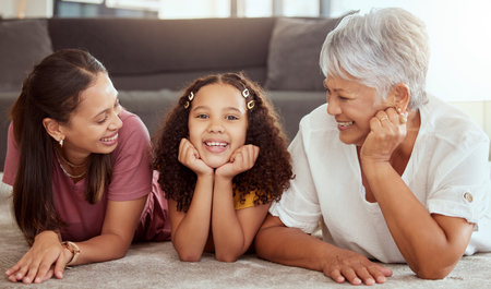 Happy, generations and smile with family on floor of living room for bonding, relax and love in house. Happiness, portrait and grandmother with young child, mom and home for fun, support and togetherの写真素材