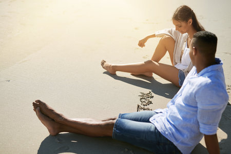Enjoying a leisurely day at their favourite spot on the beach. a young couple writing in the sand while relaxing at the beach.の写真素材