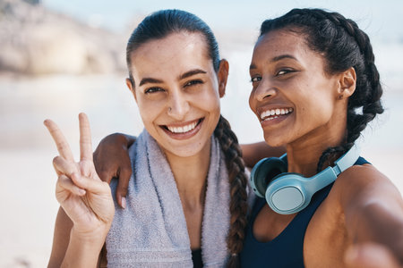 Women friends, beach selfie and peace sign in portrait for exercise, health or hug with fitness in nature. Latino girl, black woman and photography for profile picture, social network and blog updateの写真素材
