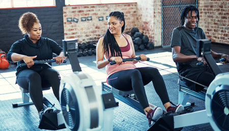 Setting and achieving fitness goals together. a fitness group working out on rowing machines in their session at the gym.の写真素材
