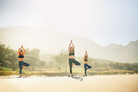 Yoga has unlimited benefits. three young women practicing yoga on the beach.