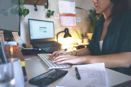 Updating all my files online. an unrecognizable woman sitting alone and wearing a headset while using her computer to work from home.の写真素材