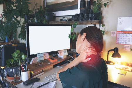 Ive put my neck out again. an unrecognizable woman sitting alone and suffering from neck ache while working from home.の写真素材