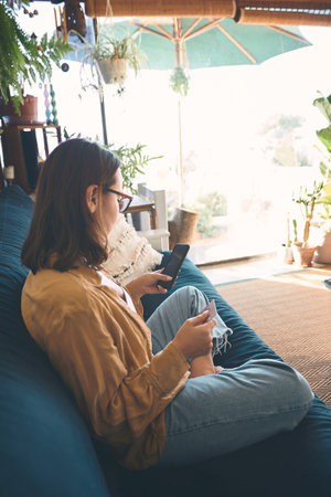Lunch is on me today. a young woman using a smartphone and credit card on the sofa at home.の写真素材