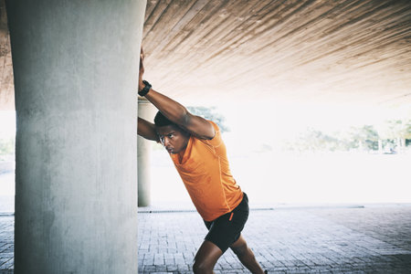 Miracles dont make muscle, discipline does. a young man stretching during a workout against an urban background.の写真素材