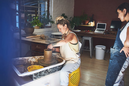 Every pot tells a piece of your story. two young women working with clay in a pottery studio.