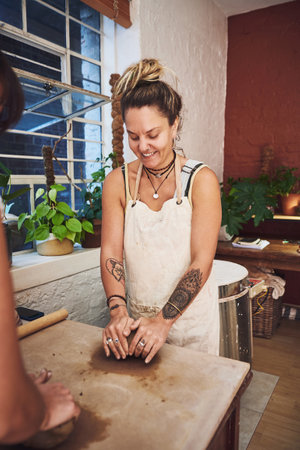 Youd smile too if you were in the pottery studio. a young woman kneading clay in a pottery studio.の写真素材