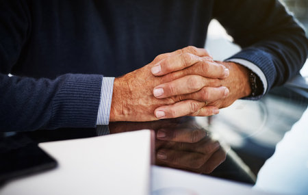 He knows his business. a businessman sitting at his work desk with his hands clasped.の写真素材